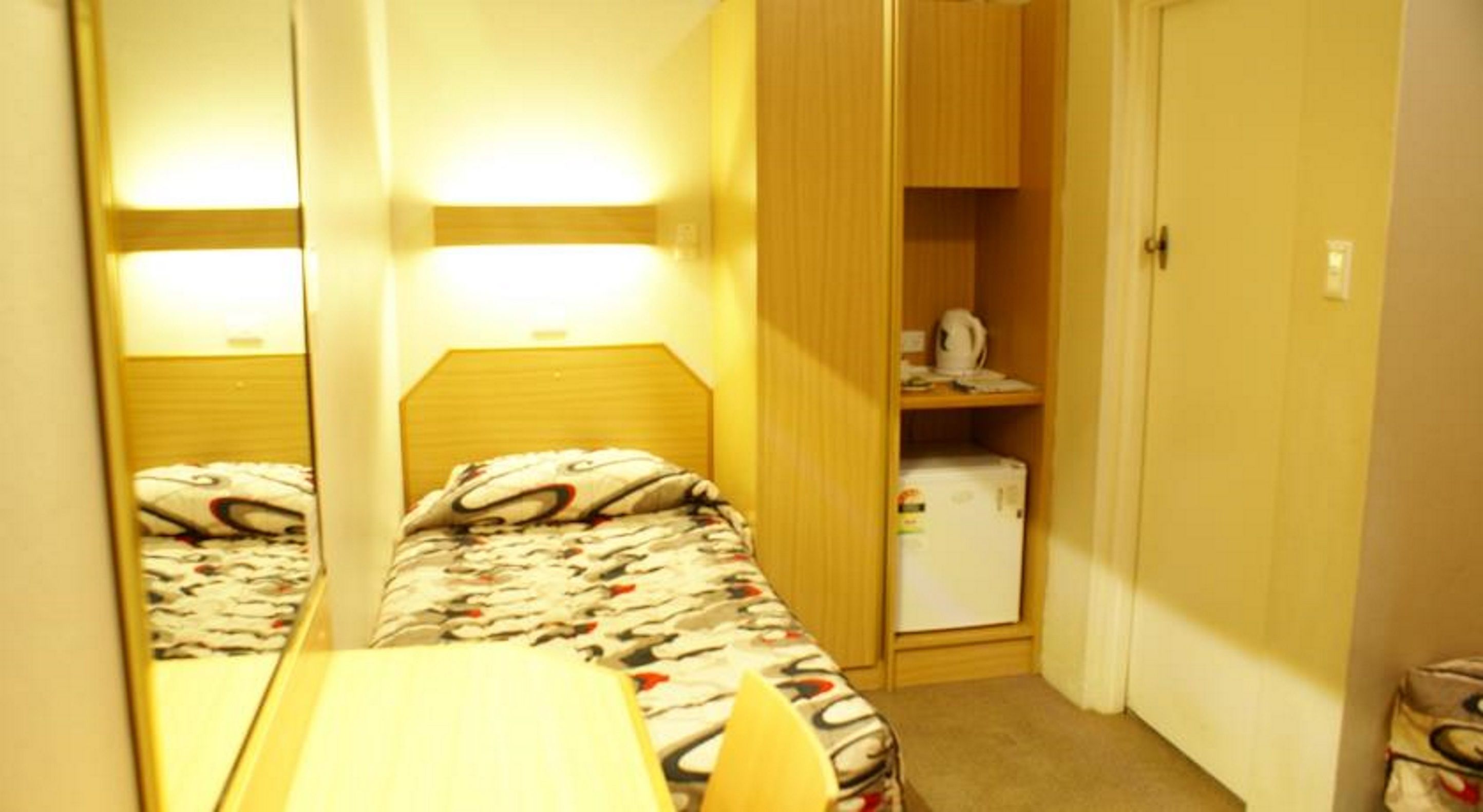 A small room with two beds, a table, and a cabinet.