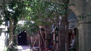 Un patio con una hamaca colgante, plantas en macetas y una rústica pared de piedra.