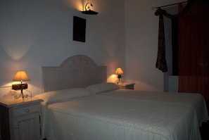 Cama bem arrumada com duas mesas de cabeceira, cada uma com uma luminária.