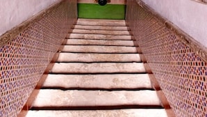 Una escalera estrecha con paredes de ladrillo texturizado a cada lado y un zócalo verde.