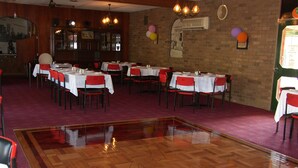 Un ristorante con diversi tavoli e sedie, un pavimento in legno e una parete in mattoni.