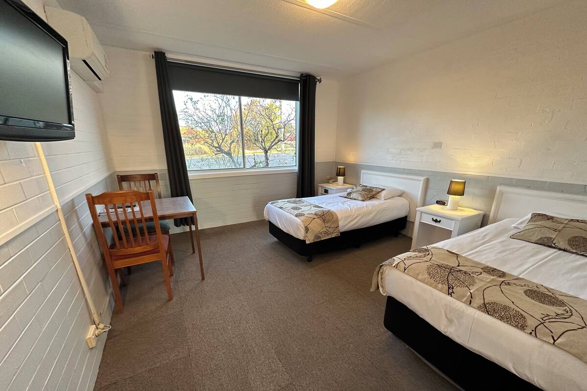 A hotel room with two beds, a desk, and a chair.