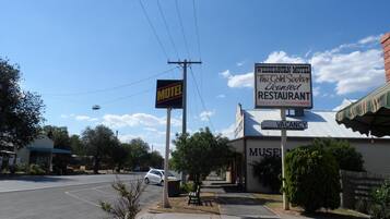 A motel with a signboard, a parking lot, and a building with a 'VACANCY' sign.