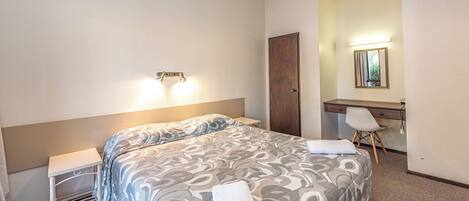 Une chambre d’hôtel avec un lit, un bureau et un miroir.