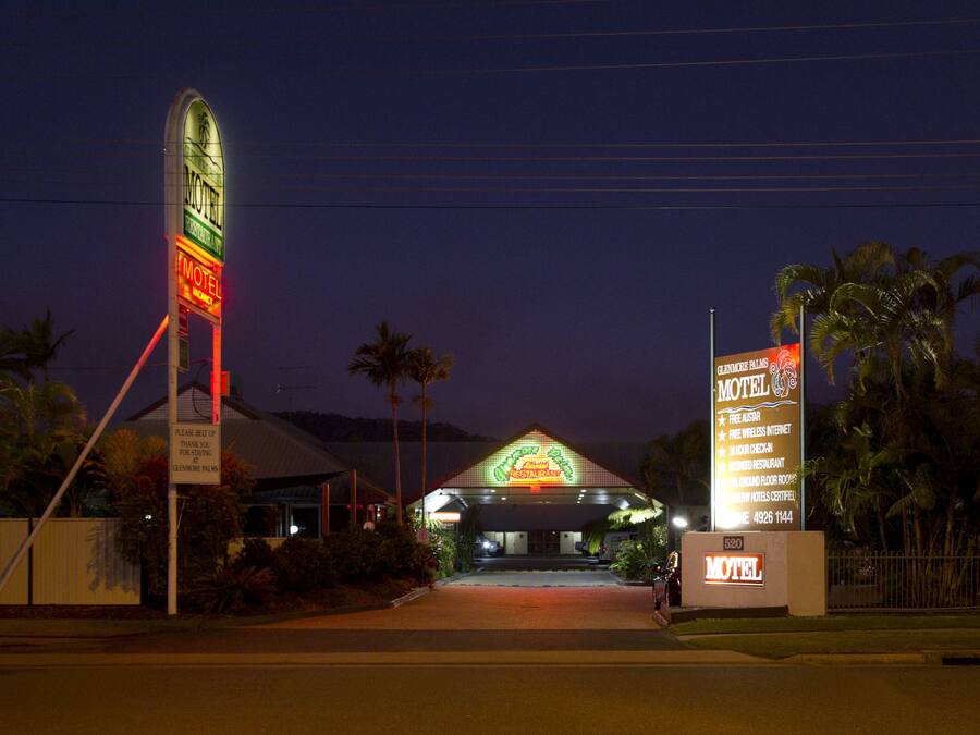Et motel med et neonskilt, palmer og en godt oplyst indgang.