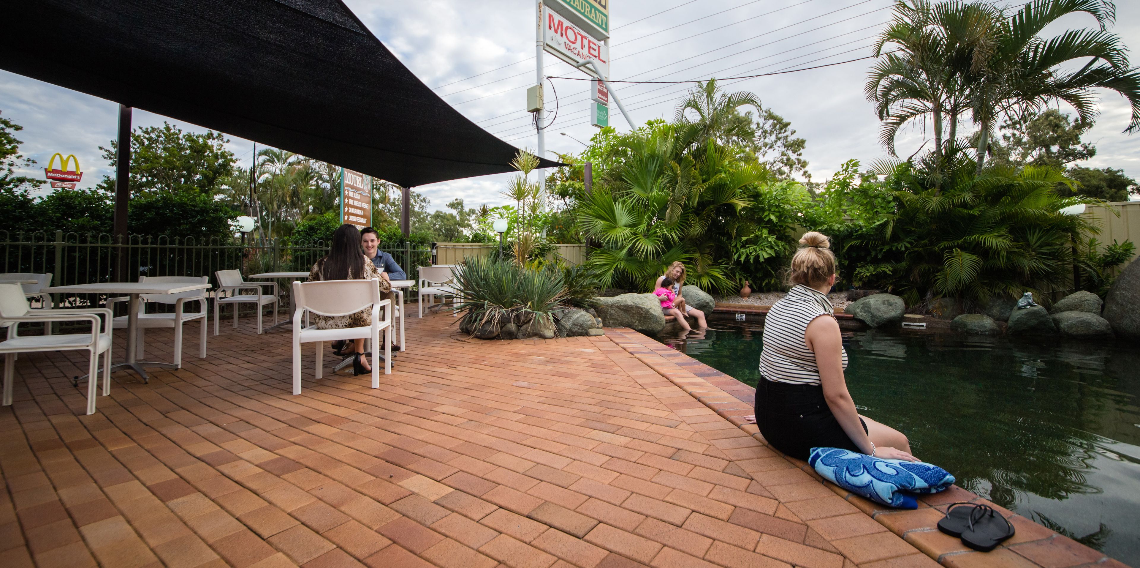 A patio area with outdoor seating, a small pool, and surrounding greenery.