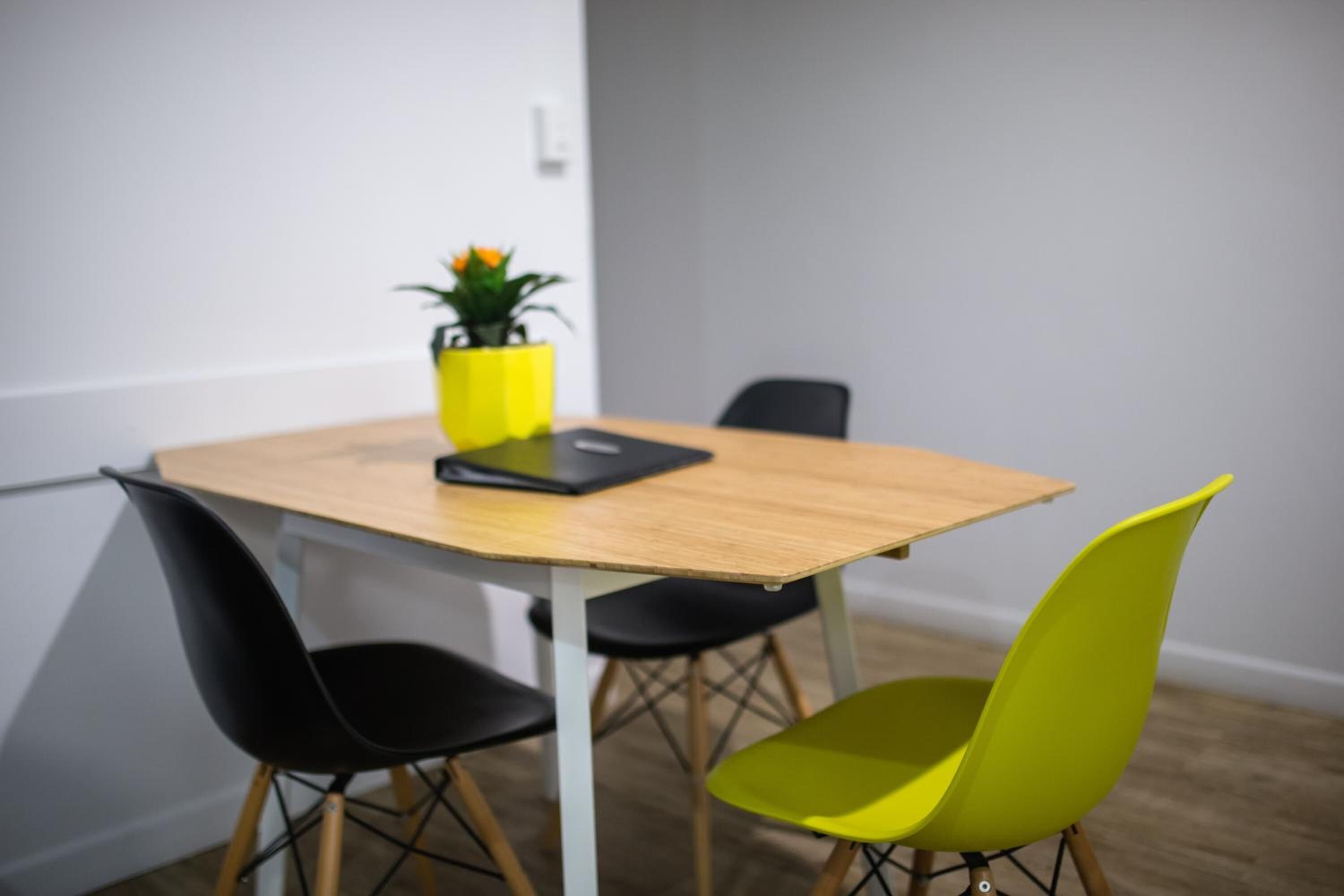 A conference room with a wooden table, black and yellow chairs, and a potted plant on the table.