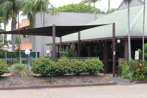 A building with a covered entrance, a metal fence, and a speed limit sign. - Glenmore Palms Motel (Norman Gardens)