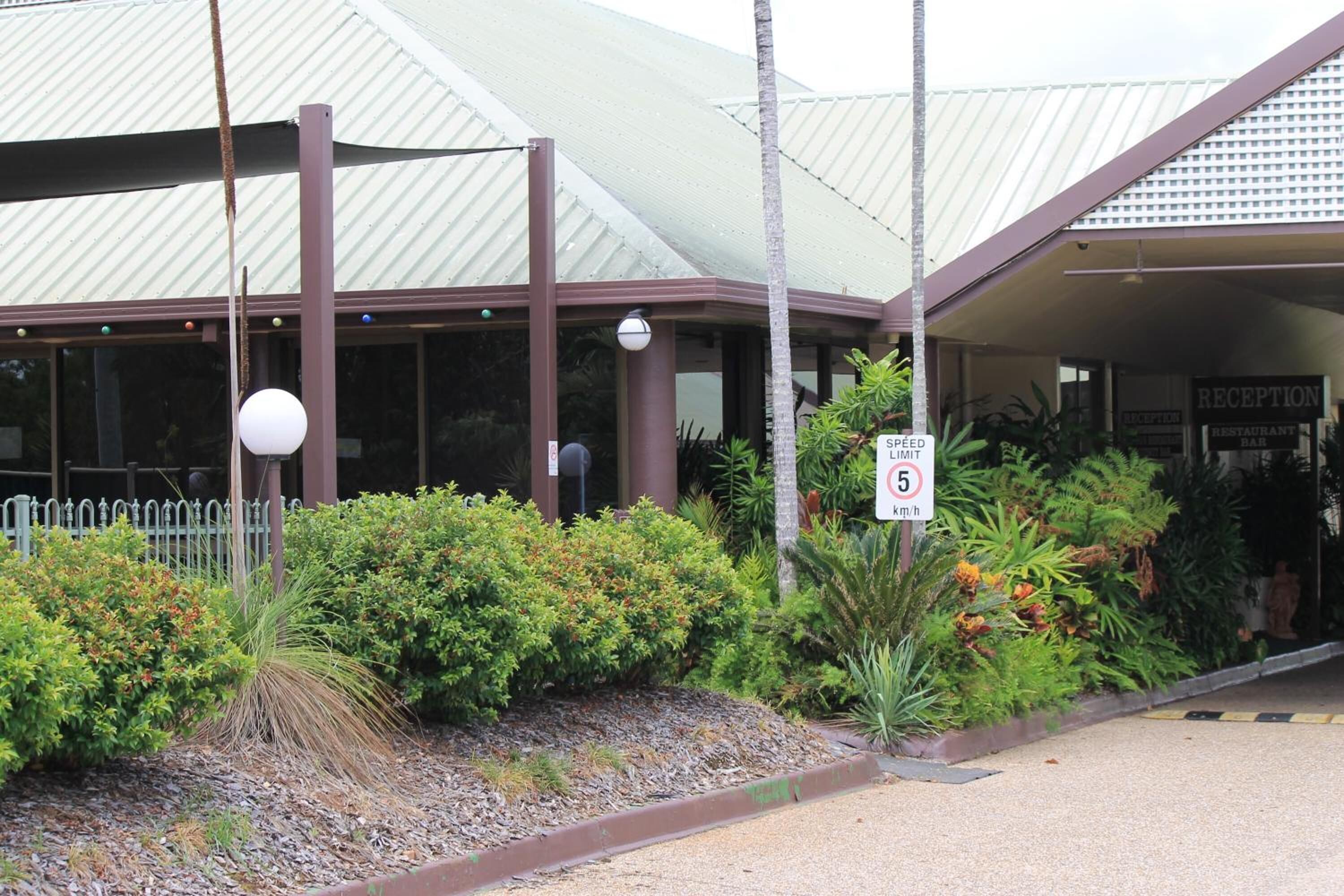 A building with a reception area, a speed limit sign, and a fenced garden.