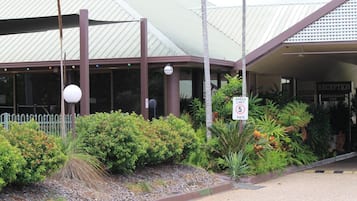 A building with a reception area, a speed limit sign, and a fenced garden.