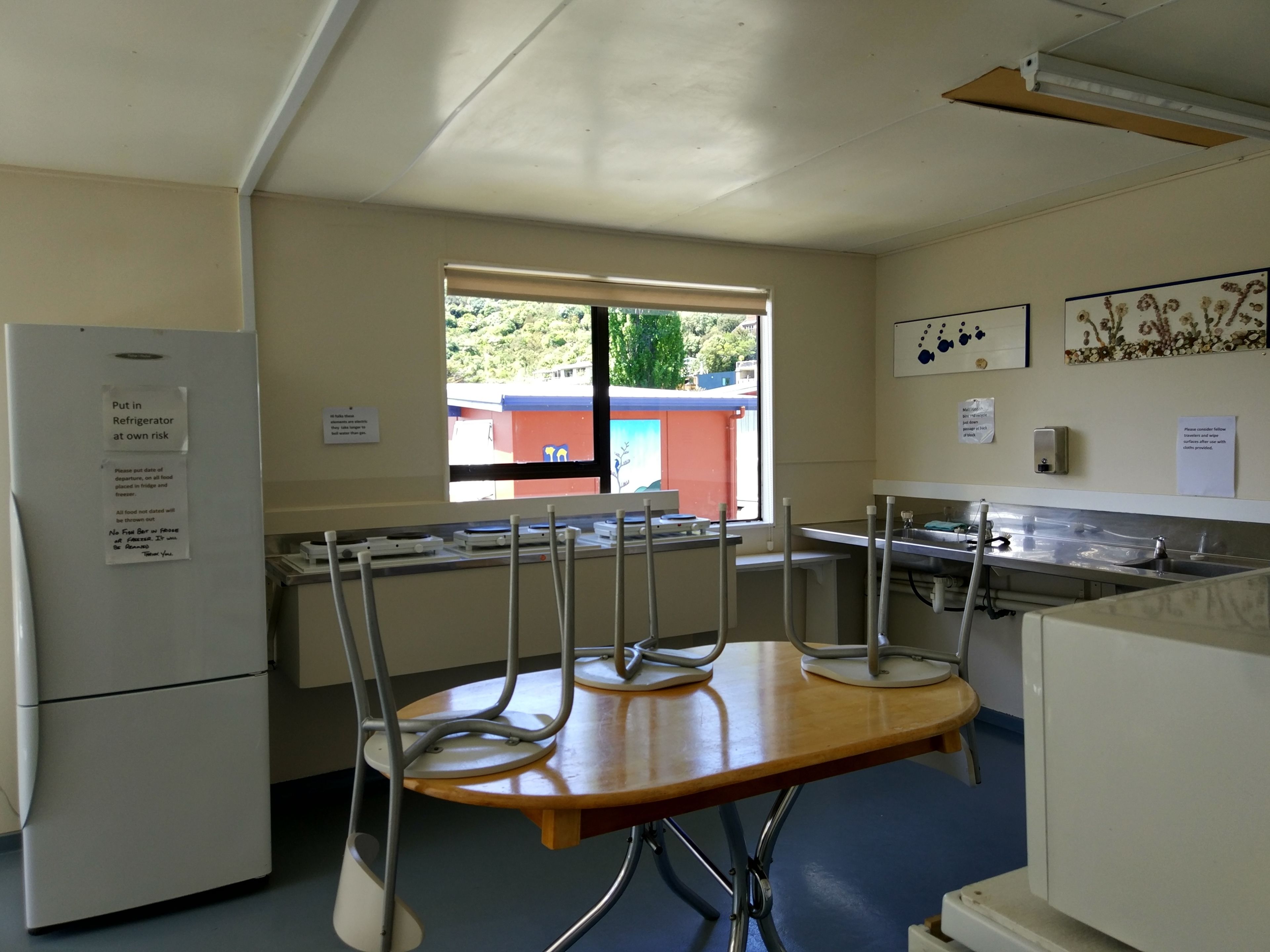 Une cuisine équipée d’un réfrigérateur, d’une fenêtre, d’un évier et d’une table avec des chaises.