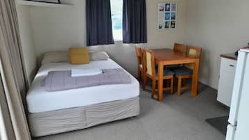A bedroom with a bed, a desk, and a chair.