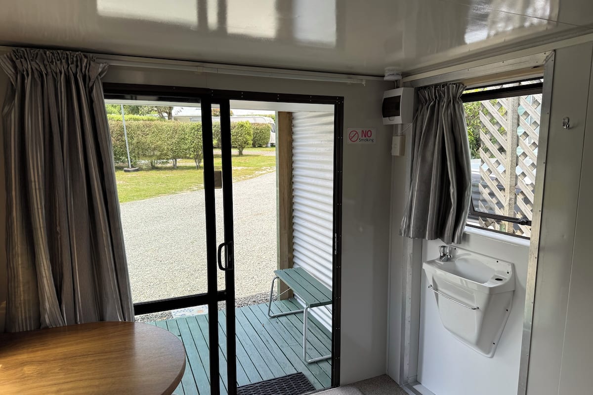 A room with a sliding glass door leading to an outdoor area, a small sink, and a table.