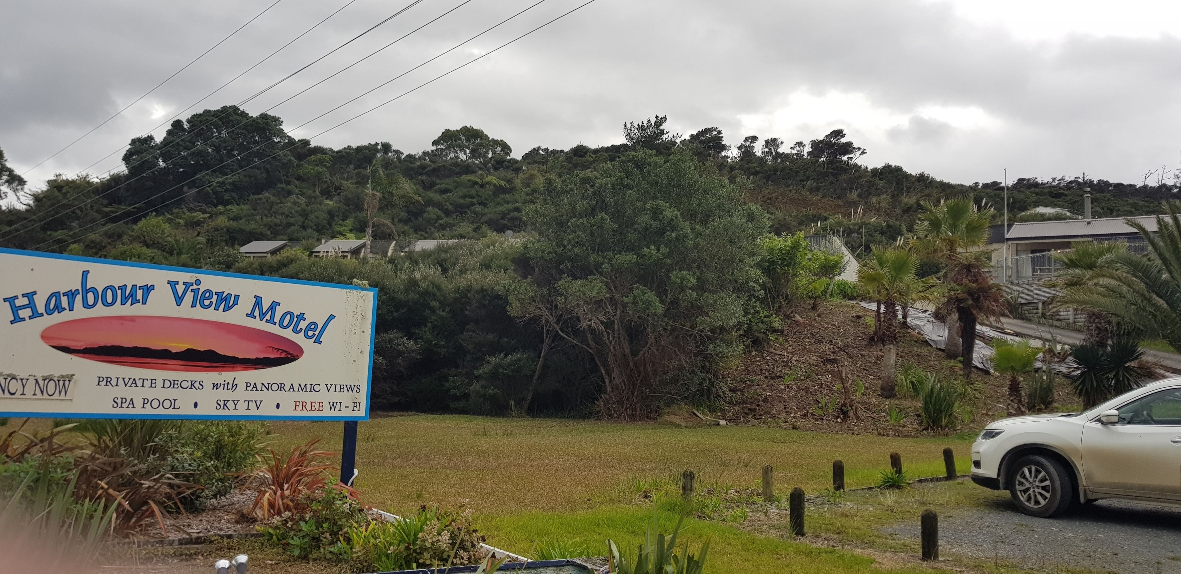 A sign for Harbour View Motel advertising private decks with panoramic views, a spa pool, sky TV, and free Wi-Fi.
