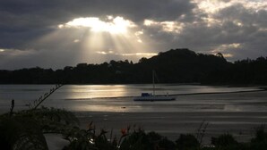 Un bote sobre aguas tranquilas, cielo nublado y una colina distante.