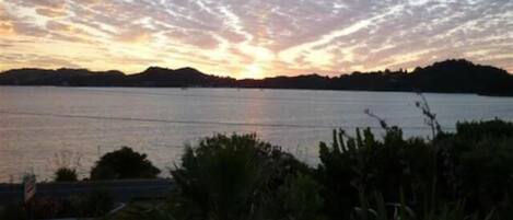 A sunset over a calm lake with distant hills.