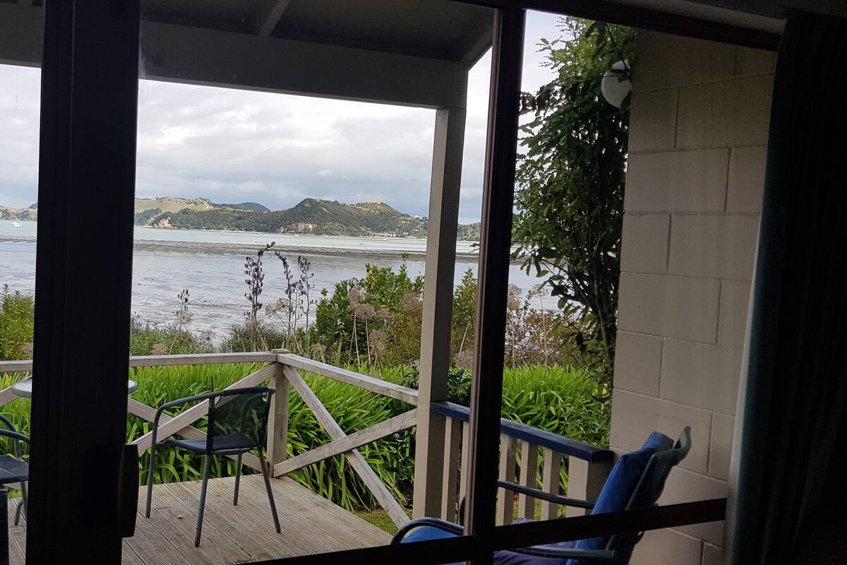 Un balcon avec des chaises et une vue sur la mer et les collines.