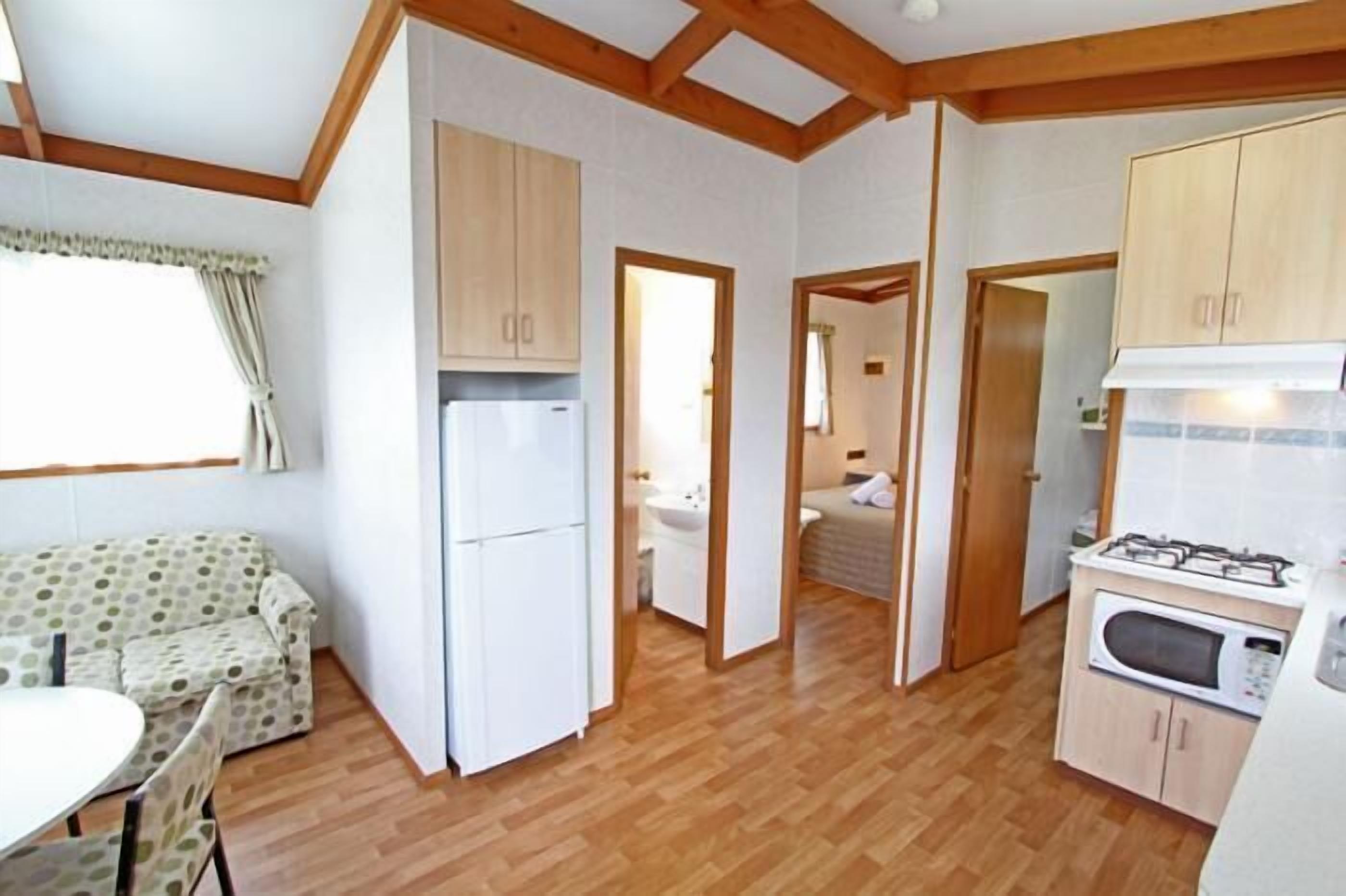 Una cocina compacta con armarios de madera, un refrigerador, una estufa y un comedor con mesa y sillas.