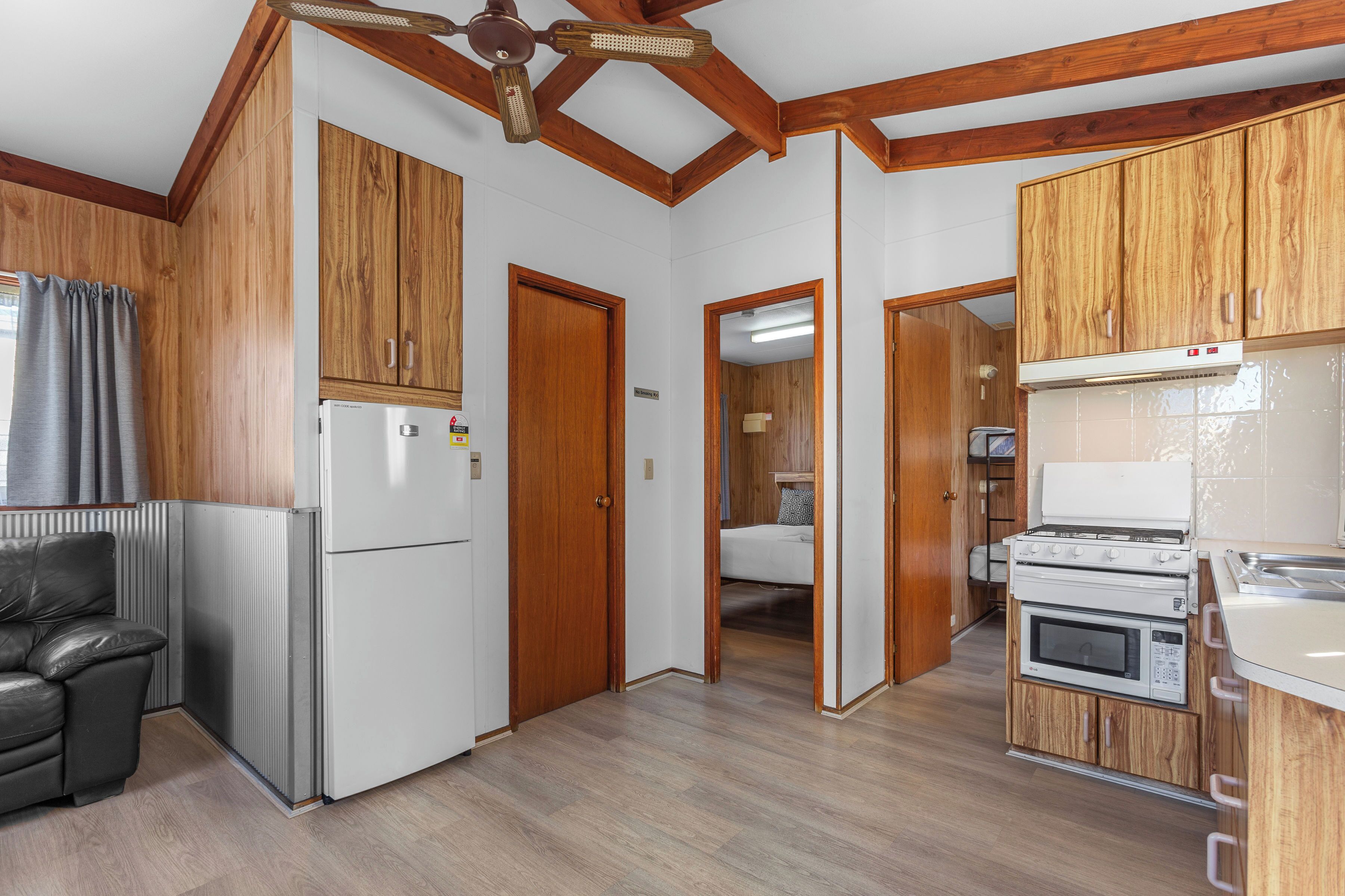 A compact kitchen with wooden cabinets, a refrigerator, a stove, and an oven.