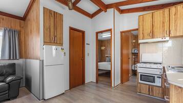 A compact kitchen with wooden cabinets, a refrigerator, a stove, and an oven.