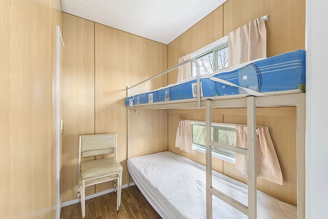 Una camera con un letto a castello, una sedia e una finestra.