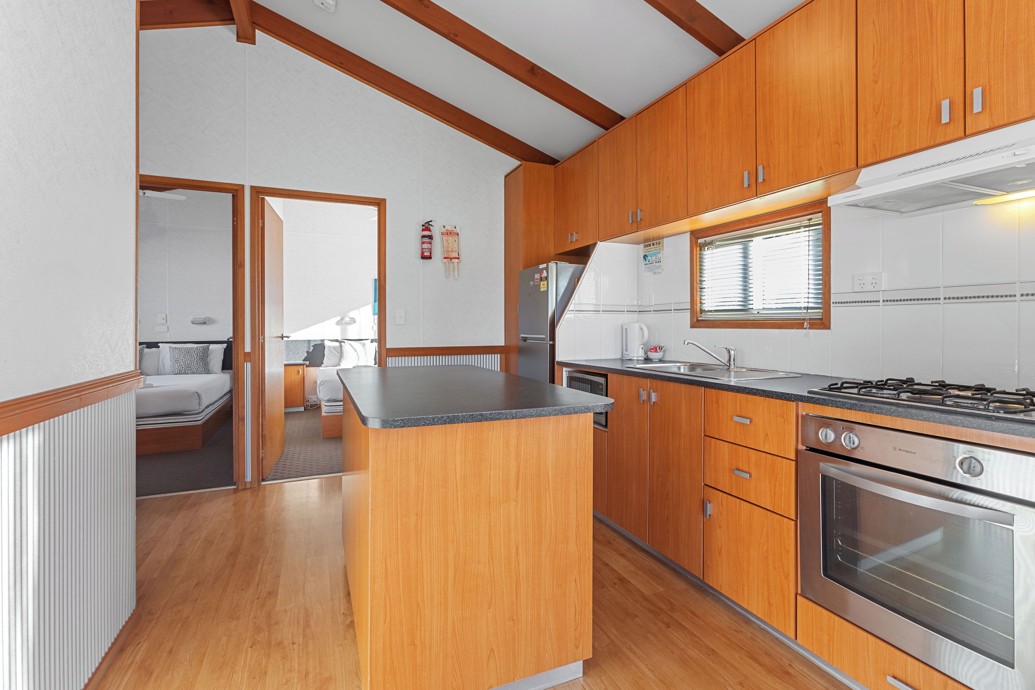 Cocina compacta con armarios de madera, una isla central, estufa y una ventana.