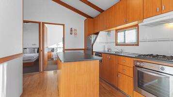 Cocina compacta con armarios de madera, una isla central, estufa y una ventana.