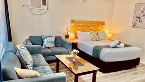 Una habitación de hotel con sofá, cama, mesita de noche y lámpara.