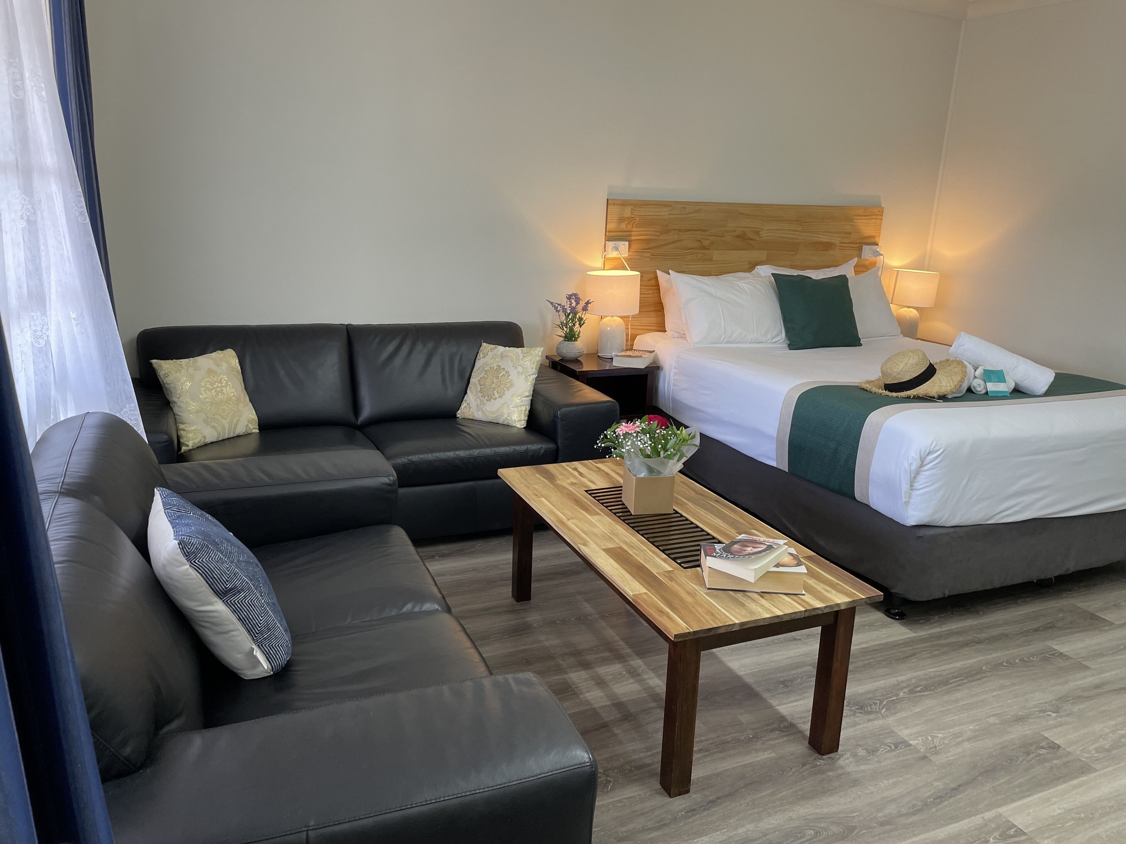 Une chambre d’hôtel avec un lit, un canapé, une table de chevet et une table.