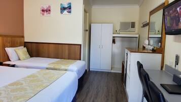 Una habitació d'hotel amb dos llits, una taula de treball, un mirall i una televisió.