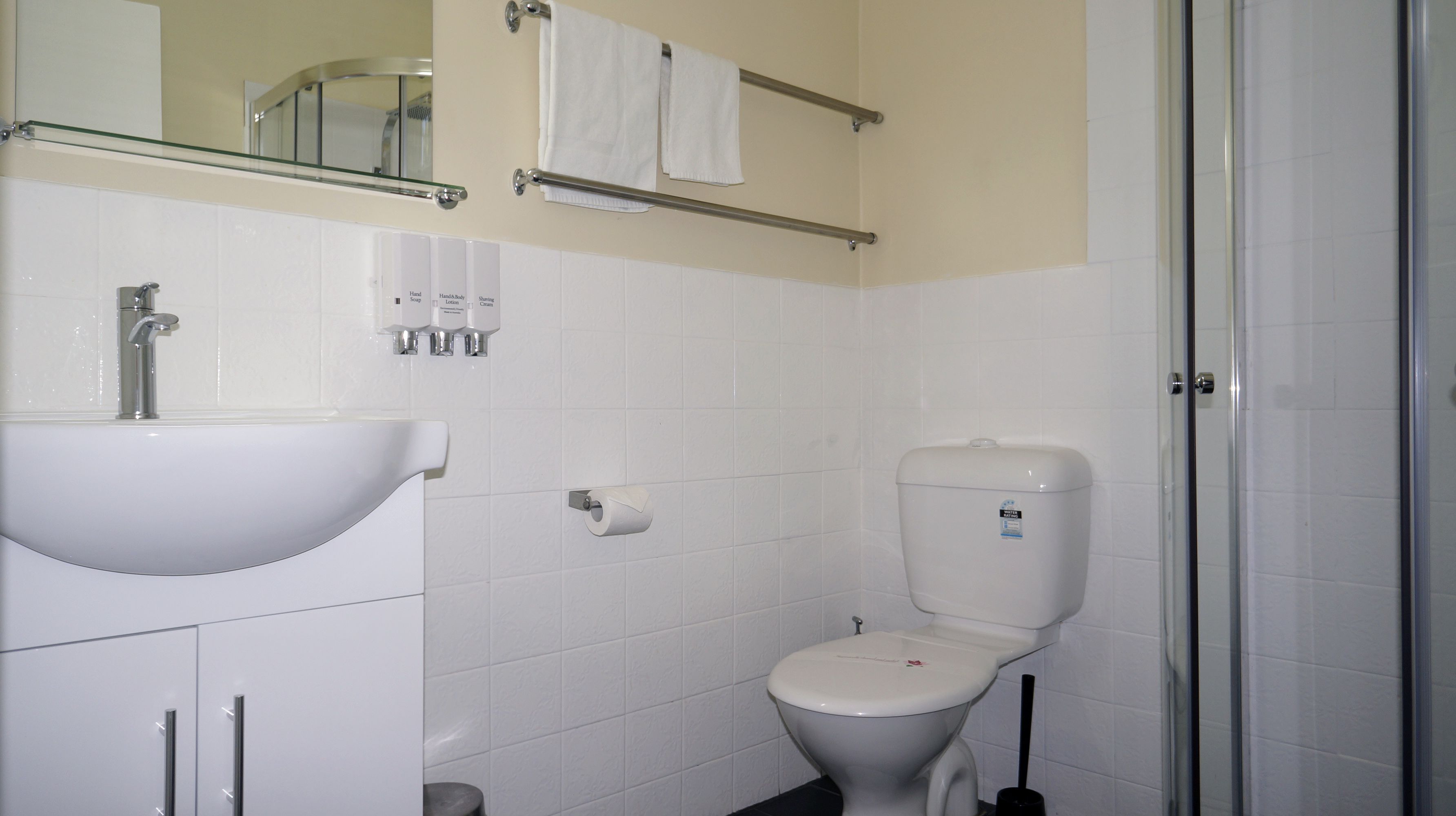 Baño con lavamanos blanco, inodoro y cabina de ducha de cristal.