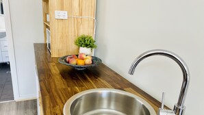 Una cocina con un lavamanos de acero inoxidable, encimera de madera y un cuenco con fruta.