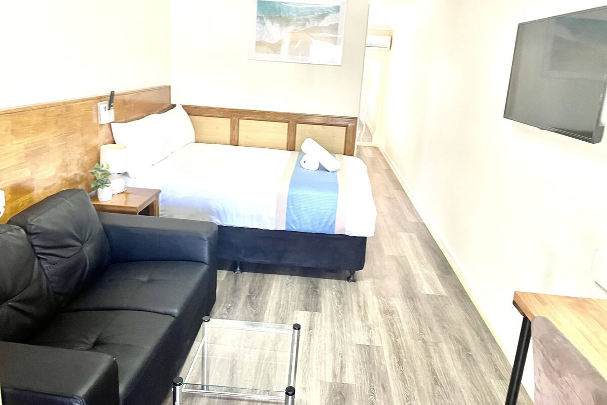 A hotel room with a bed, a sofa, a TV, and a small table.