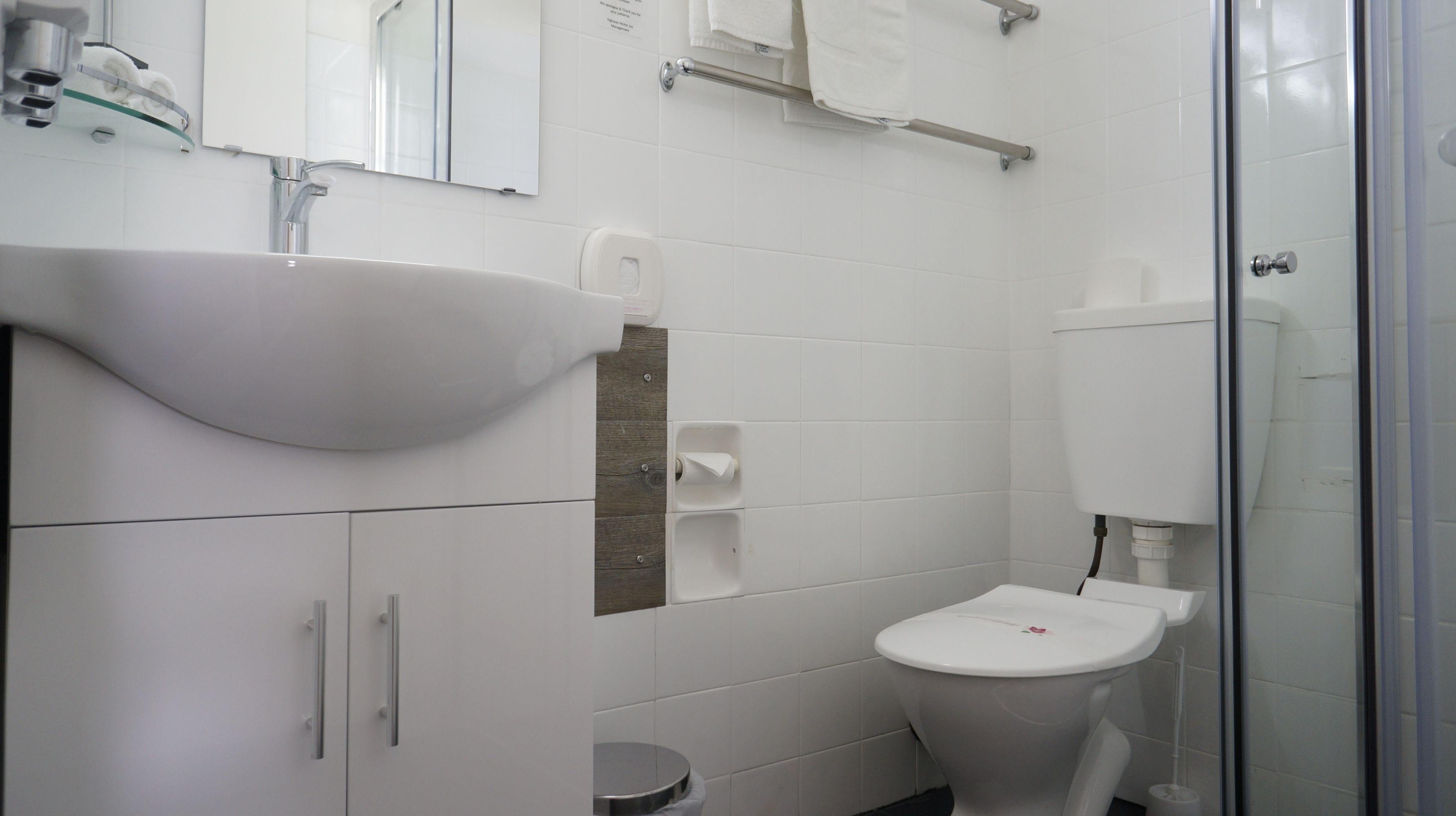 A modern bathroom with a white sink, toilet, and glass shower enclosure.
