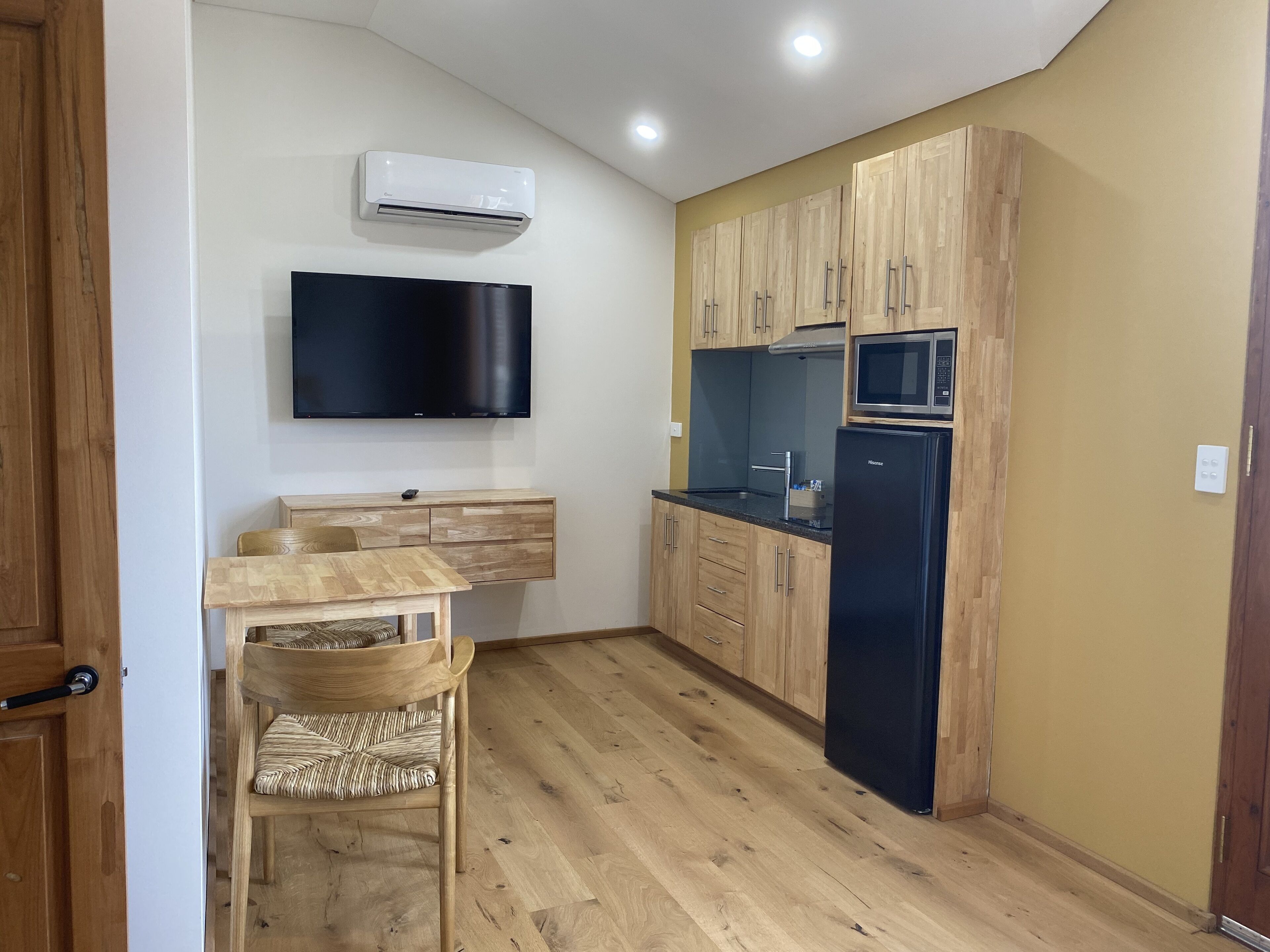 Une cuisine compacte avec des meubles en bois, un four à micro-ondes encastré et un réfrigérateur noir.