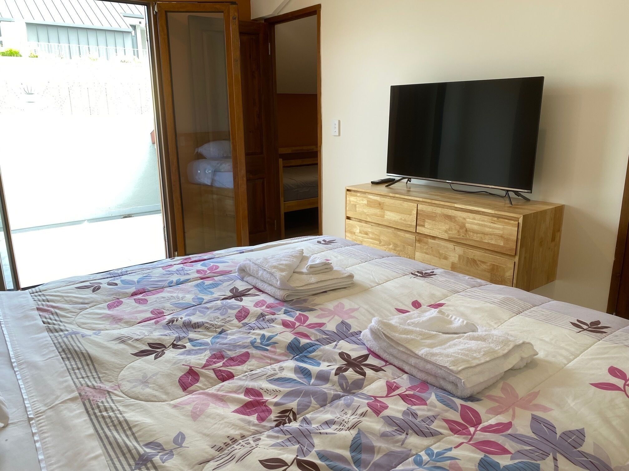 Une chambre à coucher avec un lit, un téléviseur posé sur une commode en bois et une armoire.