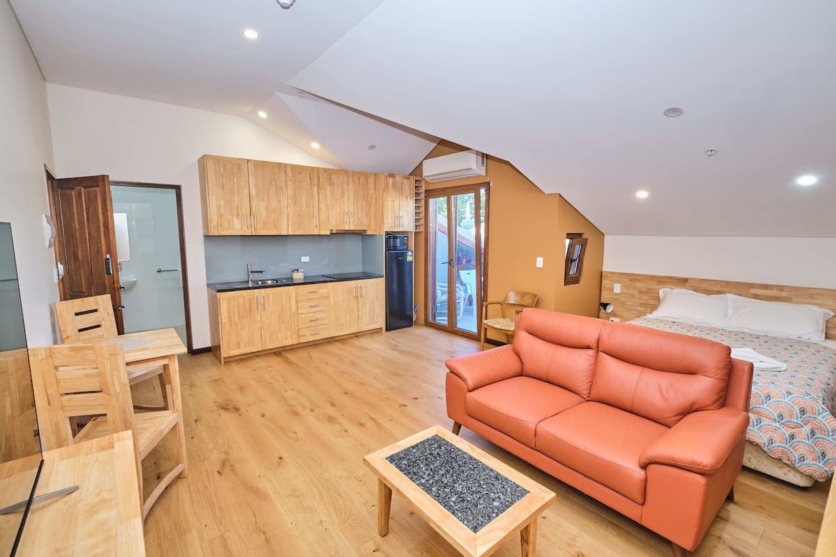 A compact living space with a kitchenette, a sofa, a dining table, and a bed.