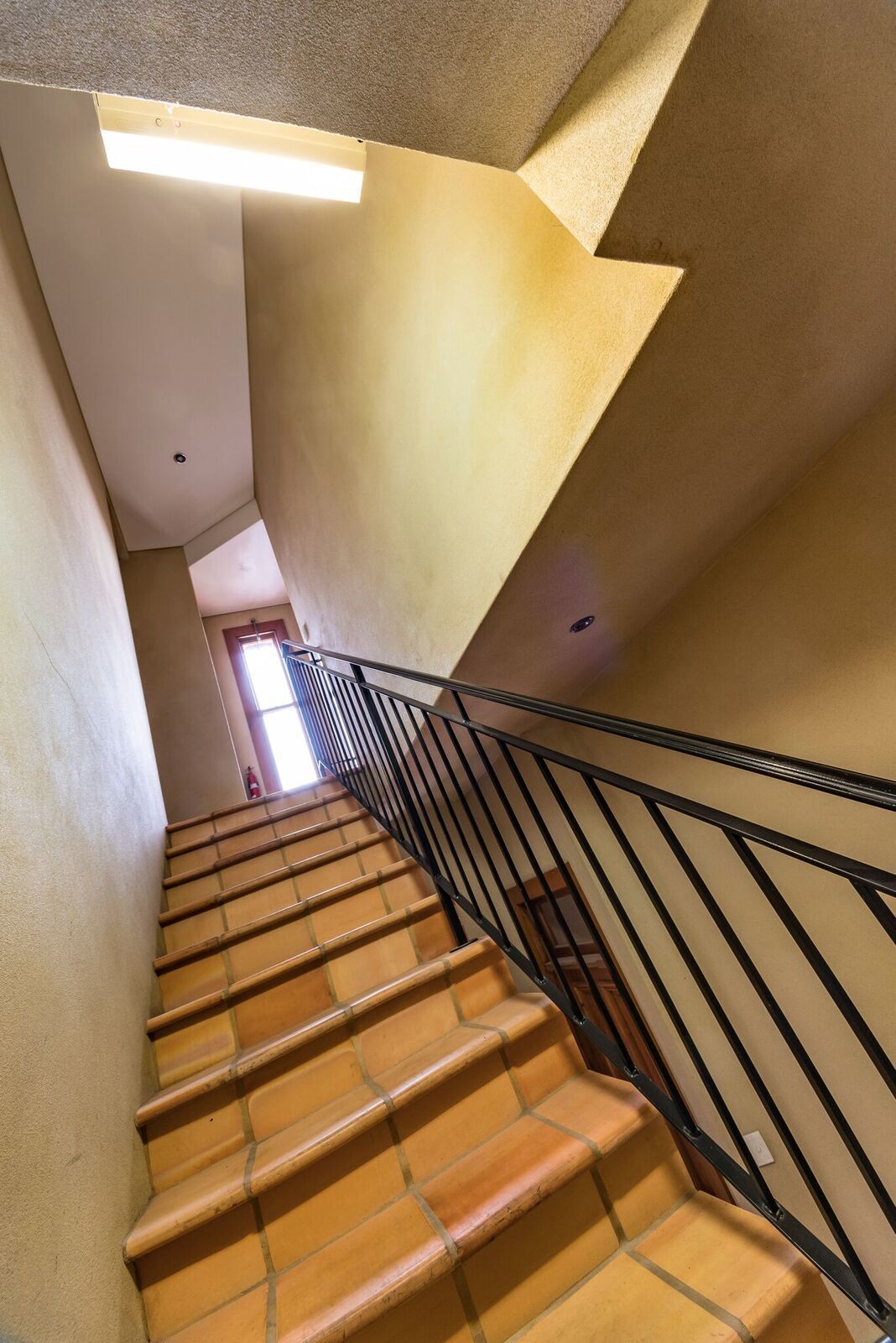Una escalera con escalones de madera y barandillas negras, que sube.