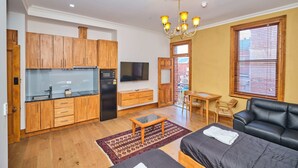A compact living space with a kitchenette, a dining area, and a seating area with a sofa and a table. - Rialto Suites (Fremantle)