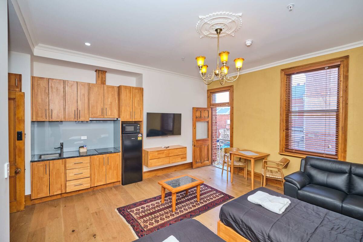 A compact living space with a kitchenette, a dining area, and a seating area with a sofa and a table.