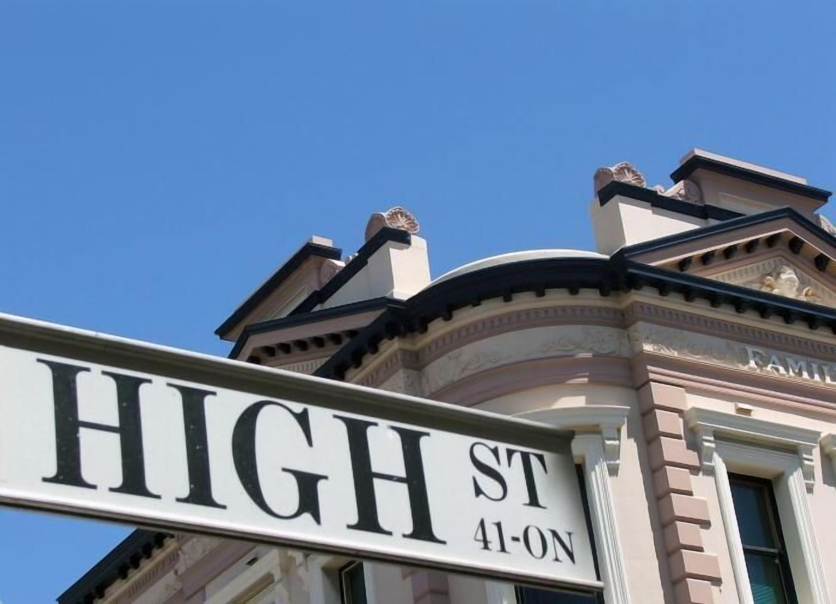 Un panneau de signalisation indiquant « High St 41-ON », avec un bâtiment de style classique en arrière-plan.