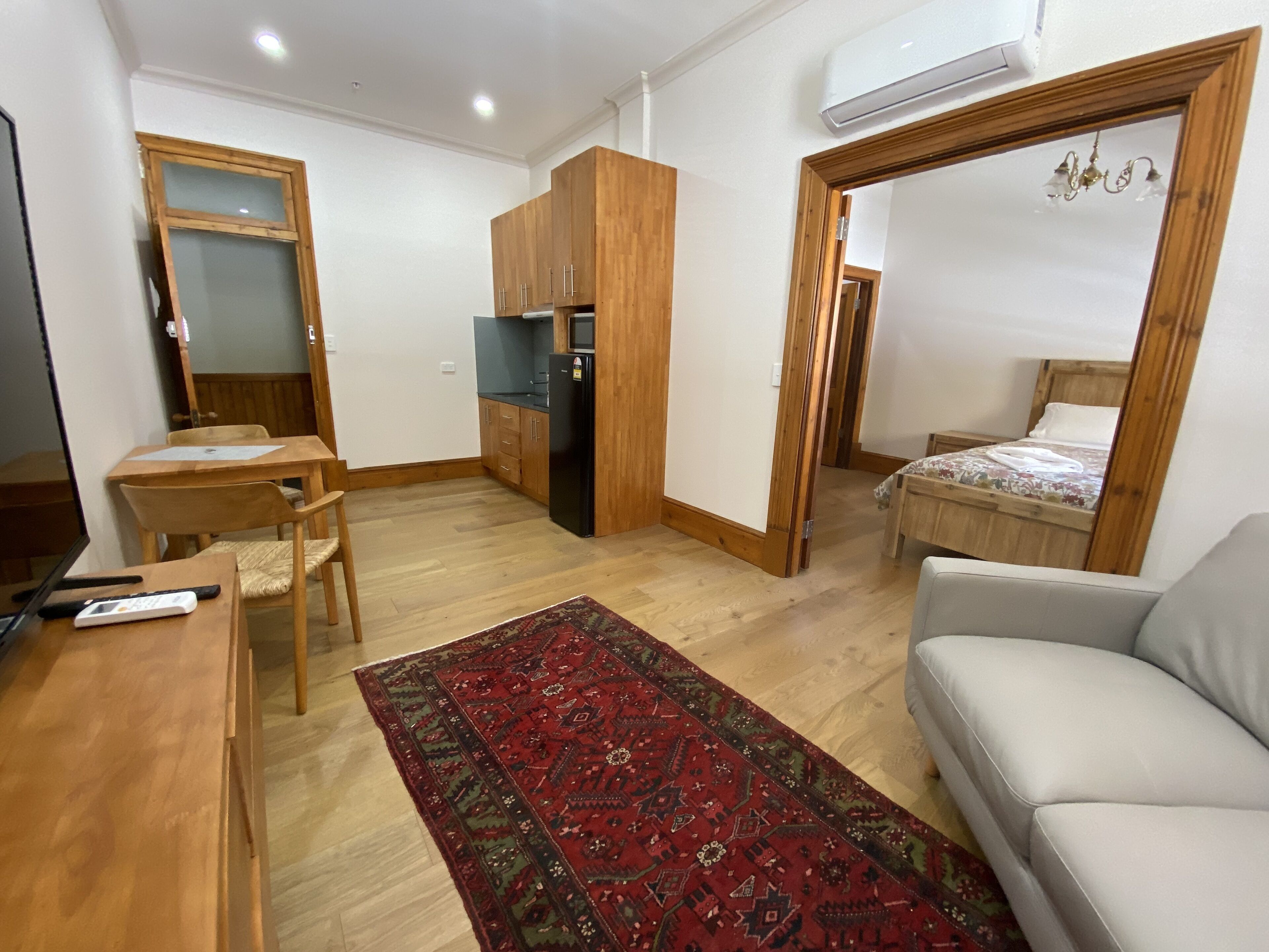A compact living space with a kitchenette, a dining area, a sofa, and a bed.