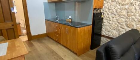 Um espaço de estar compacto com cozinha compacta, área de refeições e canto de descanso.