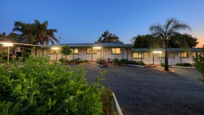 A row of motel buildings with a gravel driveway and landscaped areas. - Oasis Motel Peak Hill (Peak Hill)