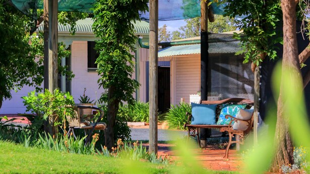 A garden with a bench, a table, and a potted plant. - Oasis Motel Peak Hill (Peak Hill)
