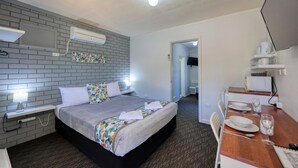 A hotel room with a bed, bedside table, lamp, air conditioning unit, and a small kitchenette area with a microwave and toaster. - Oasis Motel Peak Hill (Peak Hill)