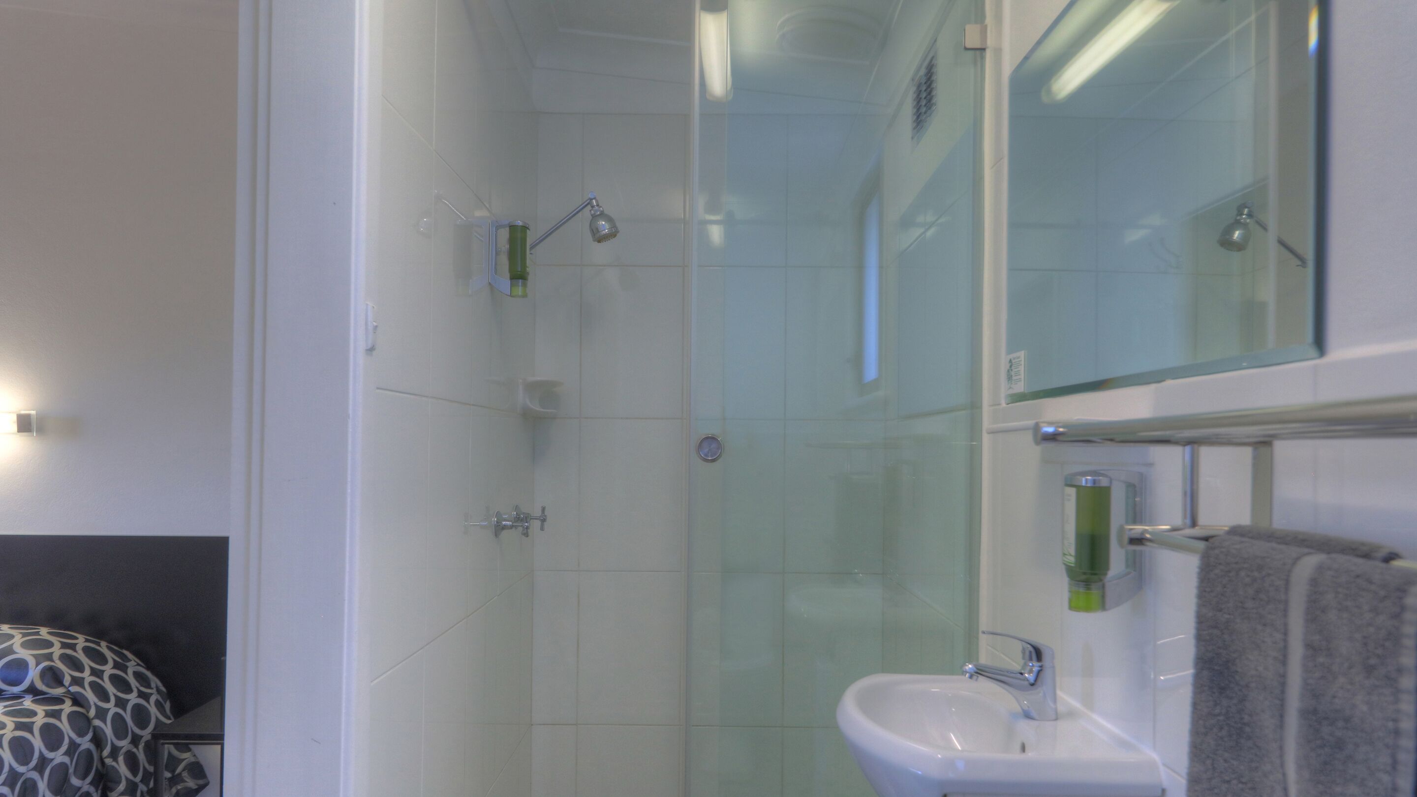 A modern bathroom with a glass shower enclosure, a white sink, and a mirror above the sink.