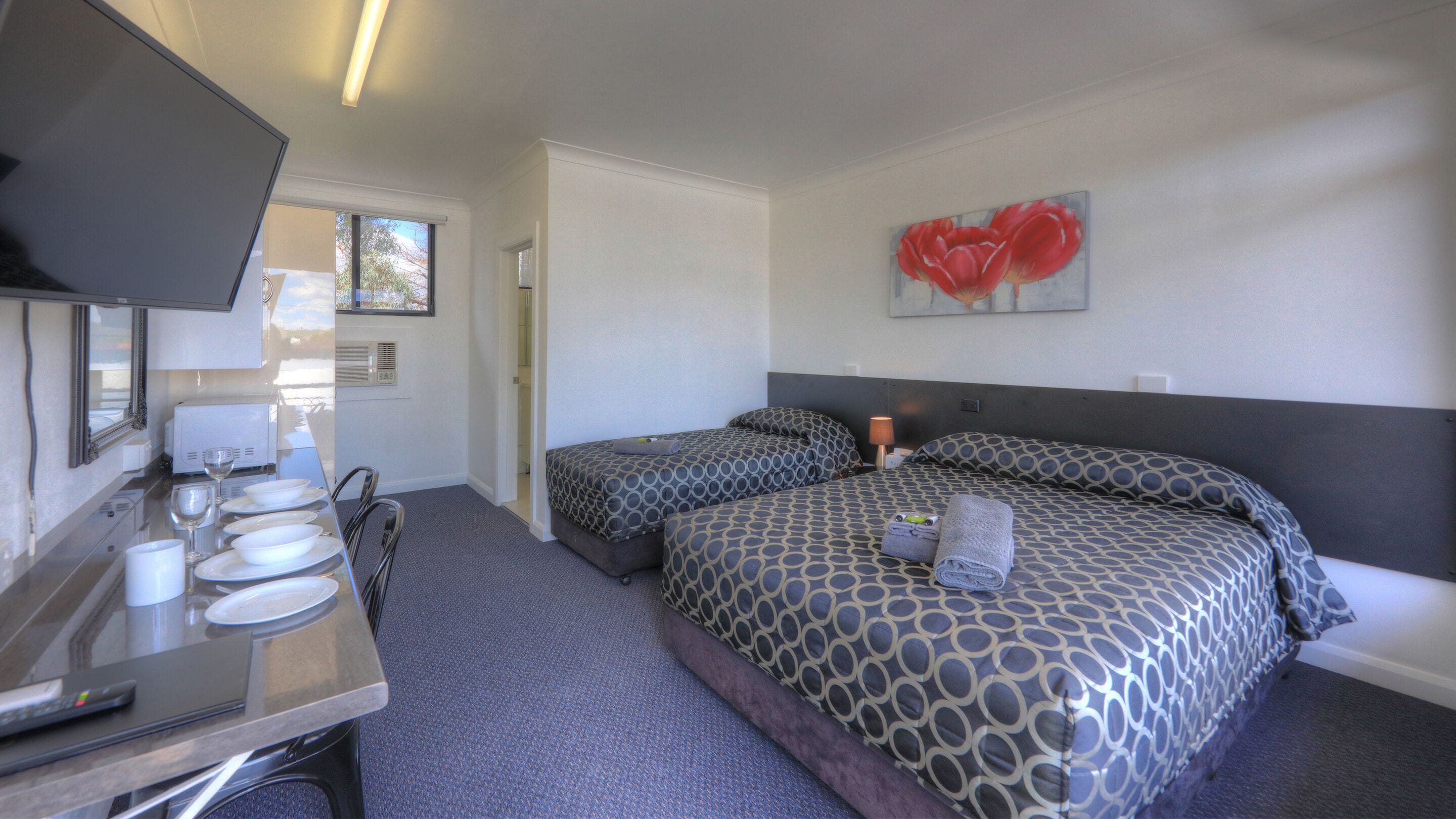 A hotel room with two beds, a desk with a computer, and a TV.