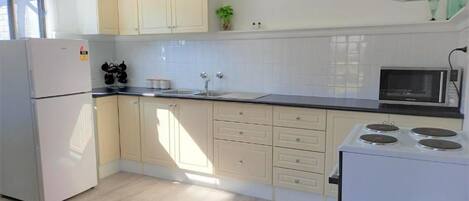 Una cocina moderna con armarios de tonos claros, un microondas integrado y una estufa.