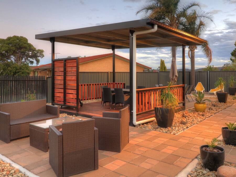 An outdoor patio area with wicker furniture, a covered seating area, and potted plants.